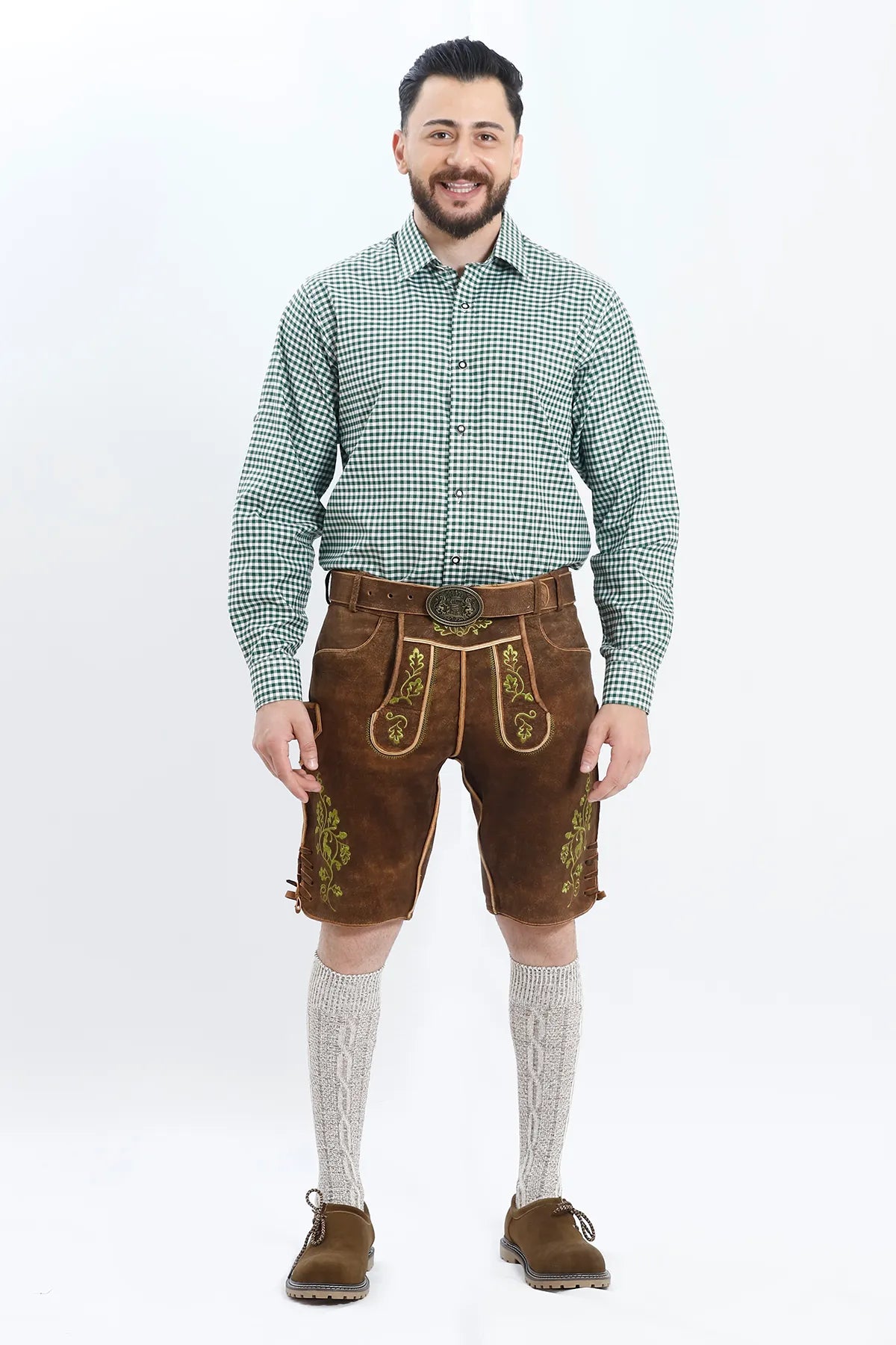 Lederhosen Men in Brown Color with Traditional Green Embroidery. Model is wearing Green Checkered Shirt with Bavarian Socks and Shoes.
